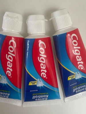 Colgate tandkräm 3-pack - Tre tuber Colgate tandkräm med röd och blå design. Tuben har vit skruvkork och tydlig Colgate-logga. Tandkrämen är avsedd för daglig tandvård och innehåller medel mot karies. Perfekt att ha hemma eller ta med på resan.