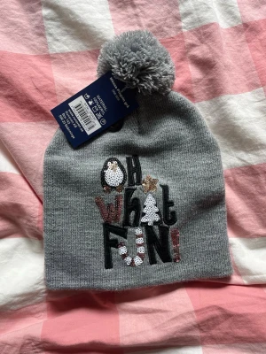 Grå mössa med paljetter och tofs - En fin mössa som aldrig är använd. Skriv om ni har frågor eller vill ha fler bilder!💞.