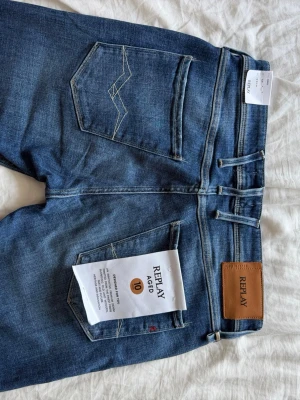 Blå jeans från Replay med raka ben - Snygga blå jeans från Replay med klassisk femficksmodell och raka ben. Jeansen har en brun läderpatch med Replay-logga bak i midjan och kontrastsömmar på bakfickorna. Tillverkade i mjukt denimtyg som ger en skön passform. Anbass modell
