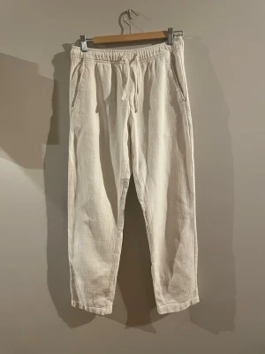 | ZARA | Beige tjockare linnebyxor med dragsko - Säljer ett par beige tjockare linnebyxor med vävd struktur och avslappnad passform. Byxorna har resår i midjan med dragsko, två sidofickor fram och en bakficka. Perfekta för chill dagar och riktigt sköna att bära. Materialet känns mjukt och följsamt. Finns svag fläckar som man anar i visst ljus vid smalbenen.
