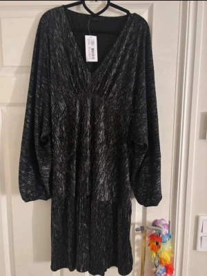 Glitterklänning - Jag säljer denna klänningen då jag inte trivdes i den. Den är ny och har prislappen kvar, den köptes för 549kr. Den är från Ellos och är i storlek L men den är ganska stor i storlek skulle jag nog ändå säga.