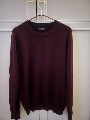 Mörkröd stickad tröja brunn & stenegade - Snygg mörkröd stickad tröja från brunn & stenegade med rund halsringning och långa ärmar. Tröjan har en minimalistisk design och är tillverkad i mjukt material som passar perfekt till höst och vinter.