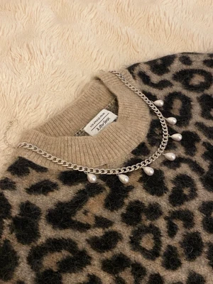 Silverfärgat halsband med pärldroppar - Snyggt halsband i silverfärgad rostfritt med kedja och hängande droppformade pärlor. Perfekt accessoar för att lyfta din outfit med en trendig och elegant touch. Passar till många olika stilar och är lätt att matcha.
