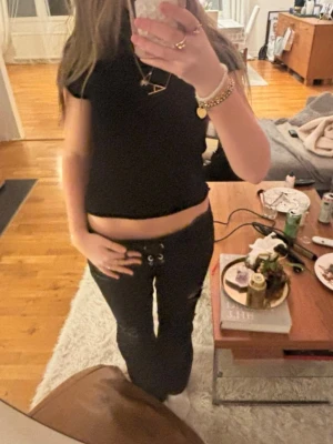 Svarta snörade jeans från Gina Tricot str M - Säljer ett par svarta jeans från Gina Tricot med snörning i midjan och slitna detaljer på benen. De är i jättebra skick och storlek M