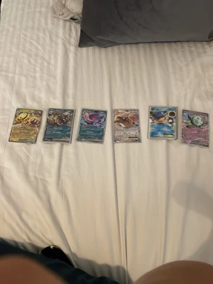 Pokémonkort samling, 6 st - Säljer ett set med sex Pokémonkort i plastfickor. Blandade motiv och färger, inklusive vatten-, el- och psykisk-typ. Perfekt för samlare eller dig som vill utöka din kortlek. Alla korten har unika illustrationer och detaljerade effekter.