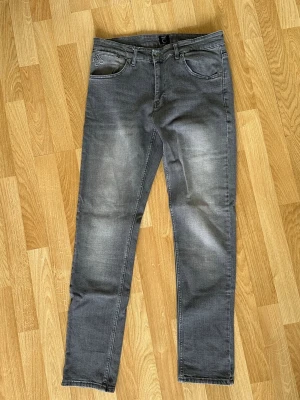 Hugo Boss Jeans - OANVÄNDA! Snygga grå slim fit jeans från BOSS med klassisk femficksmodell och diskret slitning på låren. Jeansen har normal midja, dragkedjegylf och svart BOSS-lapp bak i midjan. Perfekta för en stilren och modern look.