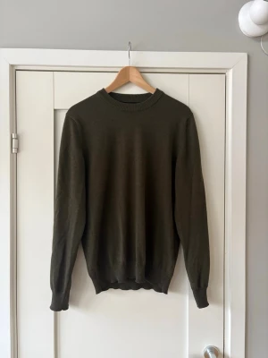 Mörkgrön Stickad J.Lindeberg tröja - Stickad mörkgrön tröja från J.Lindeberg i 100% merinoull. Köptes ny på NK för 1599kr. Helt ny med alla tags kvar. Först till kvarn!