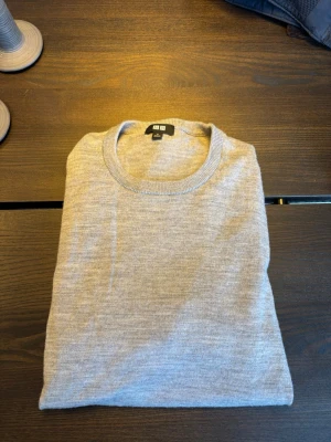 Grå stickad tröja från Uniqlo - Snygg och enkel grå stickad tröja från Uniqlo i mjukt material. Tröjan har rund halsringning, långa ärmar och ribbade muddar vid ärmslut och nederkant. Pris kan diskuteras!