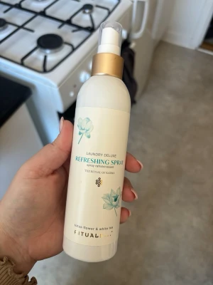 Rituals Laundry Deluxe Refreshing Spray - Fräsch doftspray för kläder från Rituals, Laundry Deluxe Refreshing Spray med lotusblomma och vitt te. Flaskan är vit med guldigt sprayhuvud och har blommiga detaljer. Perfekt för att ge textilier en uppfriskande doft.