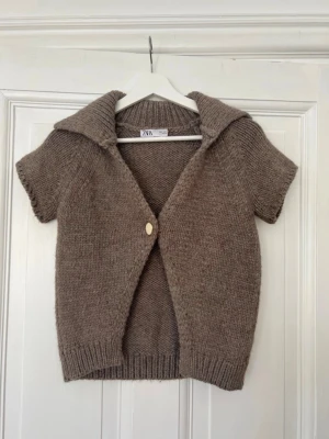 Beige stickad kortärmad kofta Zara - Skitsnygg kofta utan ärmar från Zara. Säljer för att jag inte använder längre. Skriv vid frågor eller funderingar.