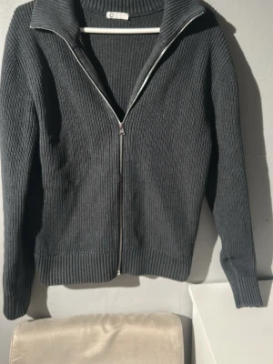 Mörkgrå ribbad ziptröja från C - Mörkgrå ziptrpja ifrån Cubus. Den är storlek S. Inga difekter eller missfärgning på den. Skriv vid funderingar och pris!!!