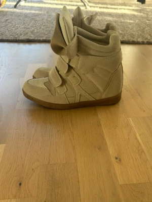 Beige höga sneakers med kardborre - Snygga beige sneakers med högt skaft och flera breda kardborreband. Skorna har en chunky design med mjukt material och detaljerad panelstruktur. Använda en gång 