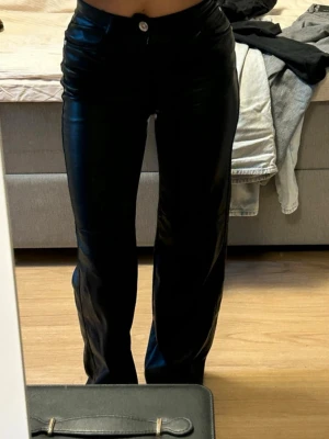 Svarta raka byxor i skinnimitation - Säljer ett par svarta byxor i skinnimitation med rak passform och hög midja.  