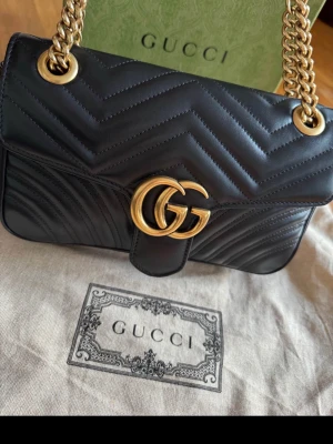 Svart Gucci Marmont handväska - Hej, Säljer denna fina Gucci väska, modell GG Marmont medium shoulder bag i original och nyskick då jag endast använt den ett fåtal tillfällen. Köpt på Gucci butiken i Stockholm. Dust bag, kvitto och kartong finns kvar. Nypris 27 200 kr Mitt pris 20 000kr