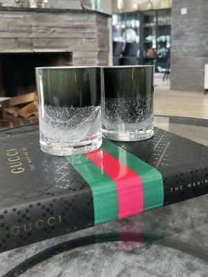 Gucci The Making Of bok - Säljer boken 'Gucci: The Making Of' med svart hård pärm och ikoniskt grönt och rött band över omslaget. Perfekt för dig som gillar mode och vill ha en snygg coffee table-bok med lyxig känsla och stilren design.