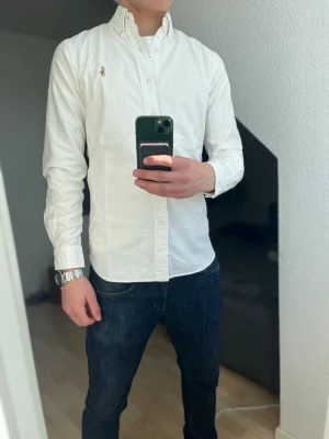 Vit Ralph Lauren Skjorta - Säljer nu min schyssta Ralph Lauren skjorta! Otroligt gott skick, perfekt inför sommaren! Storlek S, Slim Fit✅ Modellen på bild är 175 och väger ca 65kg. Har riktigt fet färg vid nedre sidan av skjortan, (se bild 5). ❗️Fraktar alltid inom 24h!❗️