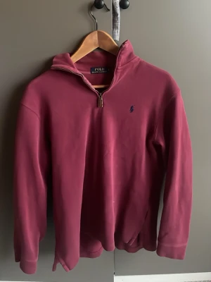 Vinröd halvzip från Polo Ralph Lauren - Stilig vinröd tröja med halvzip och broderad logga på bröstet från Polo Ralph Lauren. Tröjan har långa ärmar och klassisk passform, perfekt för dig som gillar stilrena plagg. Materialet är mjukt och bekvämt.                                               Hör gärna av dig vid frågor eller funderingar!  Mvh Melker