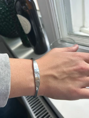 Silverfärgat stjärnmönstrat armband - Snyggt armband i silverfärg med ingraverade stjärnor längs hela bandet. Formen är klassisk och enkel, perfekt för att ge en cool touch till din stil. Materialet är metall och designen är stilren utan extra detaljer.