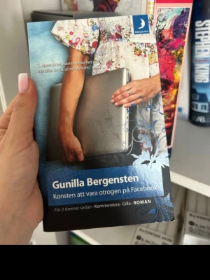 Konsten att vara otrogen på Facebook - En roman av Gunilla Bergensten i pocketformat från Månpocket. Omslaget är blått med ett foto av en kvinna i blommig klänning som håller en laptop. Boken utforskar relationer i den digitala tidsåldern och har ett modernt, ungdomligt uttryck.