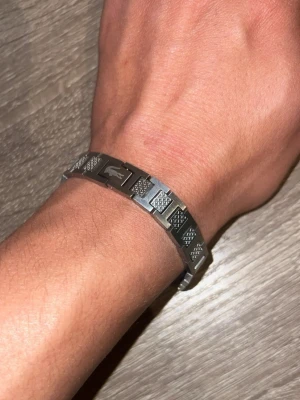 Stilrent länkarband i silverfärg lacoste - Snyggt armband i silverfärgad metall med rektangulära länkar och diskreta mönster på vissa länkar. Armbandet har en modern och clean look som passar till många stilar. Lätt att ta på och av tack vare smidig låsning.