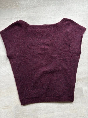 Vinröd stickad topp med korta ärmar - Mysig vinröd stickad off-shoulder topp från Nelly i mjukt material. Modellen har korta ärmar och bred halsringning, perfekt att styla med jeans eller kjol. Enkel design utan synliga detaljer eller mönster, vilket gör den lätt att matcha. Passar dig som gillar minimalistisk och avslappnad stil.