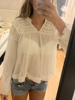 Krämvit blus från Gina Tricot - Söt vit blus från Gina Tricot med lång ärm och fina spetsdetaljer vid axlar och bröst.
