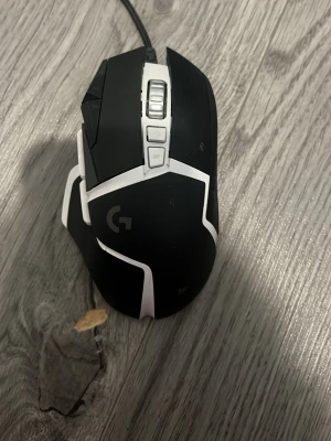 Svart och vit gamingmus med USB - Gamingmus i svart och vitt med flera knappar och scrollhjul. Ergonomisk design och ansluts via USB-kabel. Perfekt för gaming eller arbete vid datorn. Snygg och modern look med tydliga linjer och detaljer.