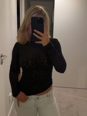 Svart mesh topp med leopardmönster - Snygg svart tajt topp med leopardmönster från Mango. Är bara använd en gång. Långärmad och figurnära modell med rund halsringning. Perfekt att styla med jeans eller kjol för en trendig look.😍😍