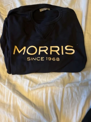 Svart sweatshirt från Morris - Snygg svart sweatshirt från Morris med stor vit logga och texten 'Since 1968' på bröstet. Klassisk rund halsringning och mjukt material som passar perfekt till jeans eller chinos.