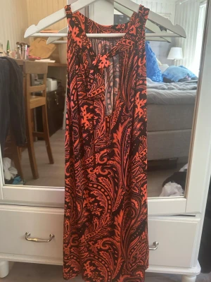 Röd kortklänning - Röd o svart mönstrad kortklänning, nyskick. I mycket bra skick! Onesize, passform XS-M