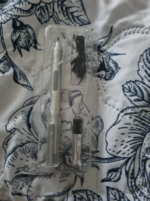 HP Active Pen med batteri och kabel - Säljer en HP Active Pen i silverfärg, perfekt för digitalt skrivande och ritande på kompatibla datorer. Pennan är tillverkad i metall och kommer med en AAAA-batteri samt en svart kabel. Smidig design med två knappar på sidan.