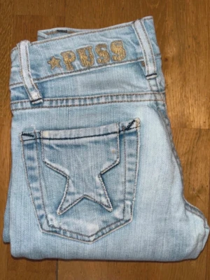 Ljusblå jeans med stjärnfickor - Märke: Puss & Kram Storlek: W24 / motsvarar cirka XS (EU 34) Material: 98% bomull, 2% elastan Färg: Ljusblå denim Skick: Mycket bra begagnat skick  Mått (ca):  * Midja: 31 cm platt mätt (+ stretch) * Innerbenslängd: 80 cm