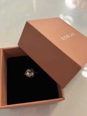 Silverfärgad ring från Edblad - Stilren ring i silverfärgat metall från Edblad. Ringen har en unik knutdesign framtill som ger en modern och trendig känsla. Inte alls mycket använd, jättebra skick! Säljer för att jag inte använder silver längre.
