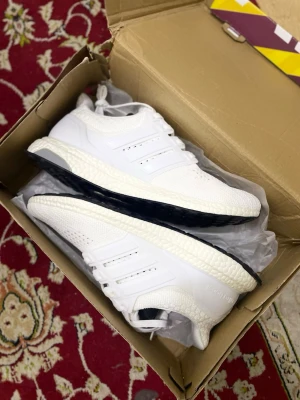 Vita sneakers Storlek 43 - Snygga vita sneakers med stickad ovandel och klassiska tre ränder på sidan. Skorna har en tjock, vit mellansula och svart yttersula för extra kontrast. Perfekta för dig som gillar en clean och sportig look. Materialet är mesh och syntet.