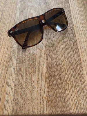 Bruna boyfriend solglasögon Ray-Ban - Snygga solglasögon från Ray-Ban i klassisk boyfriend -modell med brunmelerat skal och mörka glas. Perfekta för att lyfta din stil under soliga dagar. Tillverkade i Italien.