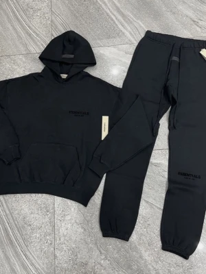 Svarta set  från Essentials - Säljer ett par svarta mjukisbyxor från Essentials med diskret logga på vänster ben. Byxorna har resår i midjan och vid bensluten samt sidofickor. Perfekta för en avslappnad och trendig look.