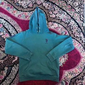 Grön hoodie från USPA med logga - Snygg grön hoodie från USPA med klassisk logga på bröstet. Hoodien har huva med dragsko och en stor magficka framtill. Perfekt för en chill och avslappnad stil. Materialet känns mjukt och bekvämt mot huden. Den passar bäst för hösten och våren men kan ändå användas under vintern o sommaren! Har bara använt 2-3ggr! Köptes för 700kr och säljs nu för 300kr eftersom jag tyckte inte om den så särskilt mycket. Kan endast mötas, gärna runt Farsta!