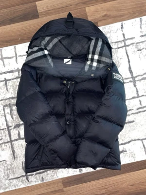Burbbery pufferjacka  - Säljer en fantastisk Burberry pufferjacka i storlek medium. Jackan är i normal storlek och har inga skador alls. Dropa längd och vikt så svarar jag ifall den passar. Är det något du undrar så kan du skriva!