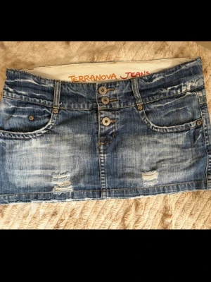 Blå jeanskjol  - Säljer en blå kort jeanskjol med slitna detaljer och rå kant. Storlek står inte men den är lite för stor för mig som brukar ha 34/36 därför skulle jag säga storlek 38. Kjolen har fyra fickor, dubbla knappar framtill och klassisk denimlook💗