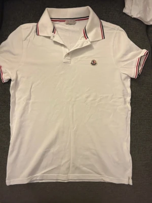 Vit Moncler Polo - Super snygg vit Moncler Polo i storlek S. Den var för liten och är helt ny och oanvänd 