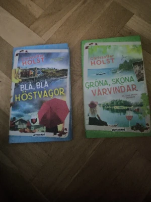 Två böcker av Christoffer Holst - Säljer två pocketböcker av Christoffer Holst: 'Blå, blå höstvågor' med blått omslag och 'Gröna, sköna vårvindar' med grönt omslag. Båda har färgstarka illustrationer och är utgivna av Lovereads. Perfekta för dig som gillar feelgood och mysiga berättelser.