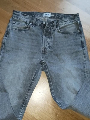 Grå raka jeans från 157 - Säljer ett par grå jeans från 157 med klassisk femficksmodell och raka ben. Jeansen har en snygg tvättad look och normal midja. Perfekta för dig som gillar en avslappnad och stilren stil.