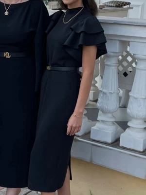 Svart klänning med volangärmar - Elegant svart klänning från Ralph Lauren med volangärmar och rund halsringning. Klänningen har ett midjebälte med RL-logga och slits i sidan. Perfekt för dig som gillar stilrena och klassiska plagg. Lite stor i storlek