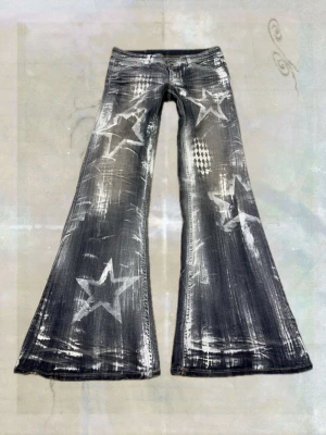 Funky fig- stjärnmönstrade jeans - Unika svarta jeans med breda utsvängda ben och coolt stjärnmönster i vitt. Jeansen har slitna detaljer och tryck både fram och bak, samt klassisk femficksdesign. Perfekt för dig som vill sticka ut med en retro och edgy look.