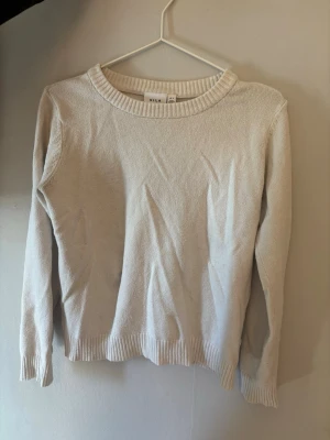 Beige stickad tröja från VILA - Beige stickad tröja från VILA med rund halsringning och ribbade muddar vid ärmslut och nederkant. Enkel och stilren design som passar perfekt till jeans eller kjol. Mjuk och skön kvalitet, perfekt för lager-på-lager under kyliga dagar.