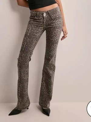 Leopardmönstrade jeans från Nelly - Snygga leopardmönstrade jeans från Nelly med raka ben och hög midja. Jeansen har klassisk femficksdesign och stängs med dragkedja och knapp. Materialet är bomull med stretch för extra komfort. Perfekta för dig som vill sticka ut med ett djurmönster.