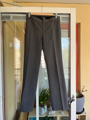 Grå randiga kostymbyxor Banana Republic storlek 32/34 - Gråa kostymbyxor med kritstrecksränder från Banana Republic. Byxorna har en rak passform och låg midja. De stängs med dragkedja och knapp framtill. Byxorna har två fickor fram och två passpoalfickor bak. Storlek US 0 (noll) motsvarar ungefär 32/34. 