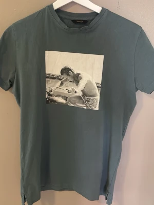 Olivgrön t-shirt med tryck från Massimo dutti  - Snygg blå t-shirt från Matinique med ett stort svartvitt fototryck på bröstet (Steve mcqueen)Klassisk rund hals och korta ärmar. Perfekt för dig som gillar coola motiv och avslappnad stil.