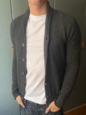 Mörkgrå stickad kofta från Massimo dutti - Mörkgrå stickad kofta från Massimo dutti, inga defekter. Modellen är 187 cm, väger 80 kg och brukar klä i M. OBS en av knapparna är sönder men det är inget som inte går att byta ut lätt hemma :)  Storlek på skjorta S/P   Leverans sker dagen efter senast. Skriv om du har nån fråga✨