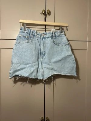 Ljusblå jeanskjol - Trendig ljusblå jeanskjol i klassisk femficksmodell med rå, fransig kant nertill. använd fåtal gånger